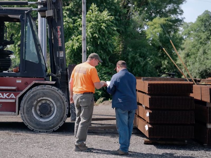 mid-city-steel-about-environmental-impact-two-workers-collaborating-near-trees-metal-forklift-800x600