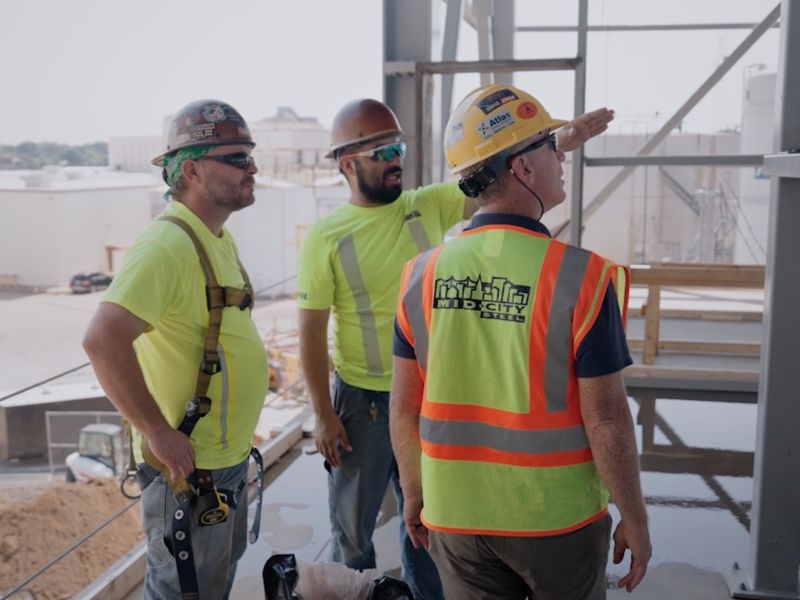 mid-city-steel-about-meet-the-team-field-and-erection-team-workers-on-site-directing-beams-800x600