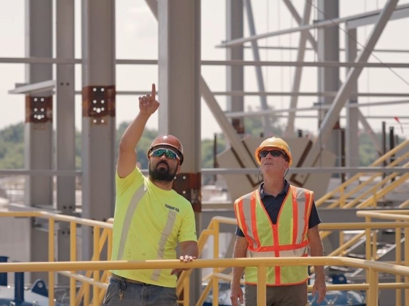 mid-city-steel-employee-on-site-metal-beams-two-workers-strategizing-800x600