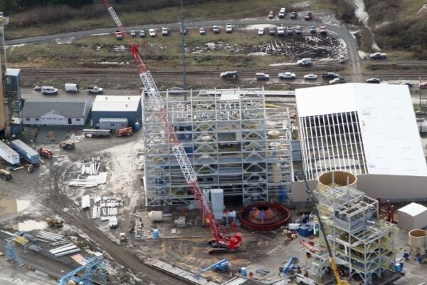 mid-city-ORC-insitutional-project-gallery-1 Aerial view of an industrial construction site with cranes, steel frameworks, and scattered building materials.