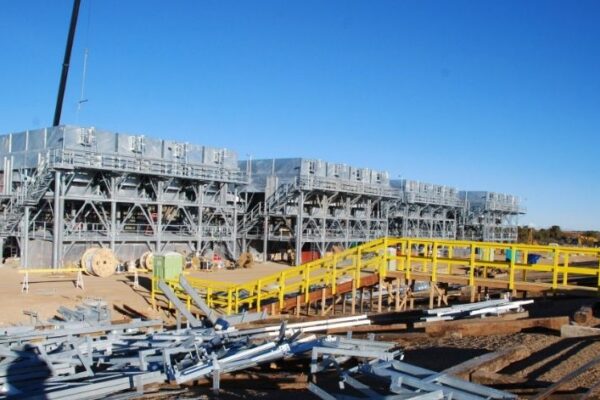 mid-city-steel-cow-canyon-central-processing-facility-industrial-gallery-10 Large industrial cooling units are under construction with yellow railings and scattered metal beams in the foreground.