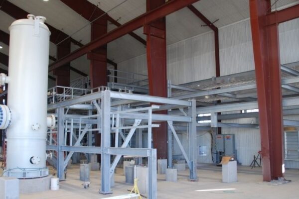 mid-city-steel-cow-canyon-central-processing-facility-industrial-gallery-11 Interior of an industrial facility with steel structures, large cylindrical tank, and red support beams.