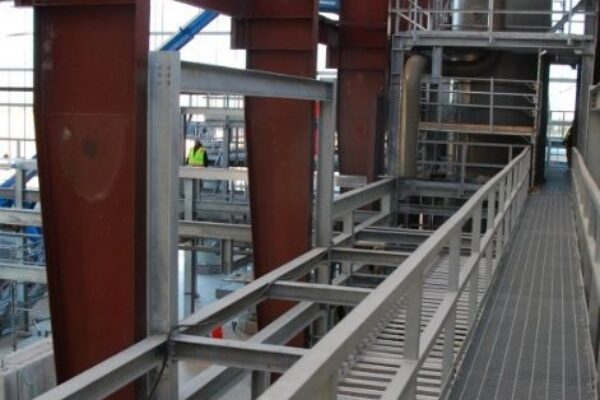 mid-city-steel-cow-canyon-central-processing-facility-industrial-gallery-12 Industrial interior with metal walkways, steel beams, and a transparent roof letting in sunlight.