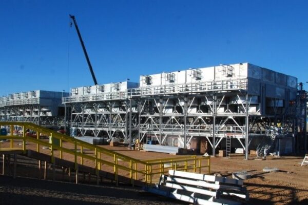 mid-city-steel-cow-canyon-central-processing-facility-industrial-gallery-7 Large industrial cooling towers and steel structures under construction at a worksite with clear blue sky.
