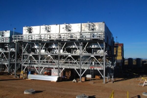 mid-city-steel-cow-canyon-central-processing-facility-industrial-gallery-8 Large industrial cooling units on metal frameworks stand on a dirt lot under a clear blue sky.