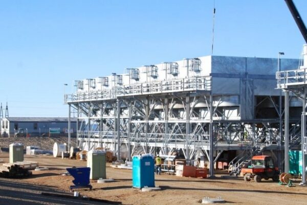 mid-city-steel-cow-canyon-central-processing-facility-industrial-gallery-9 Large industrial cooling structure under construction with equipment and portable toilets on a dirt lot.