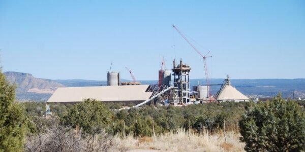 mid-city-steel-drake-cement-industrial-gallery-10 Industrial facility with cranes and large buildings under construction, surrounded by trees and distant mountains under a clear sky.