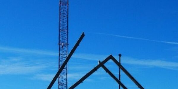 mid-city-steel-drake-cement-industrial-gallery-15 A construction site with a tall crane and steel framework for a building under a clear blue sky.