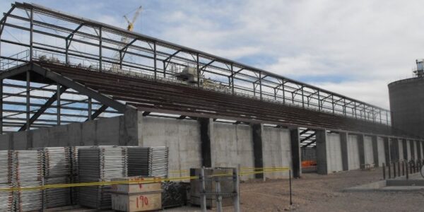 mid-city-steel-drake-cement-industrial-gallery-2 A large industrial building under construction with steel framework and concrete pillars, surrounded by equipment and materials.