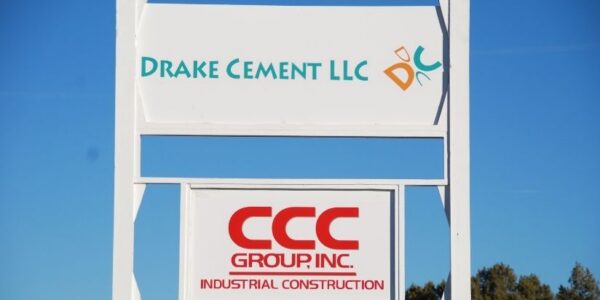 mid-city-steel-drake-cement-industrial-gallery-8 White outdoor sign for Drake Cement LLC and CCC Group, Inc. Industrial Construction, with blue sky background.