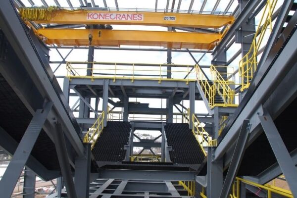 Interior of an industrial building with yellow railings and a large Konecranes overhead crane, 20-ton capacity.