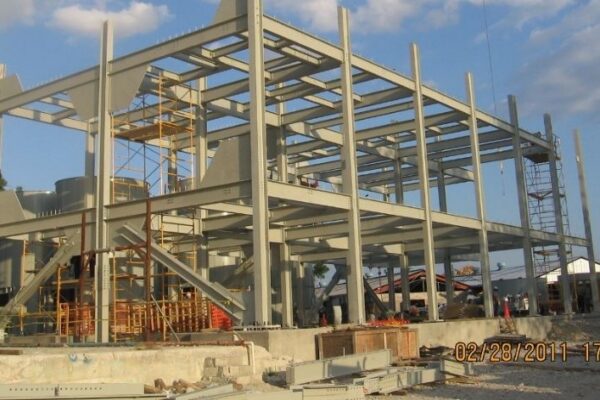 Steel framework of a multi-story building under construction, with scaffolding and construction materials around.