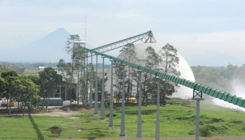 mid-city-steel-la-union-sugar-special-project-gallery-3 A green conveyor belt leads to a large white dome surrounded by trees, with a distant mountain in the background.