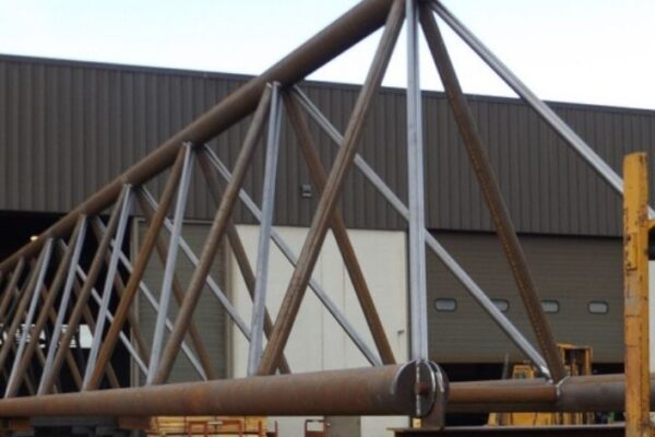 mid-city-steel-mid-city-steel-milwaukee-intermodal-station-special-project-gallery-1 A large steel truss structure is positioned outside an industrial warehouse building.