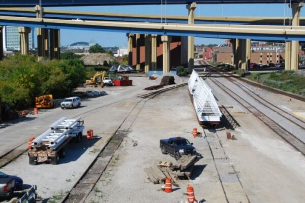 mid-city-steel-mid-city-steel-milwaukee-intermodal-station-special-project-gallery-14 Construction site with large bridge beams, trucks, and equipment near multiple elevated highways and train tracks.