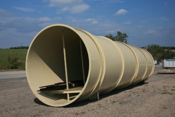 mid-city-steel-pattison-frac-sand-plant-industrial-project-gallery-3 Large, light tan cylindrical metal tunnel structure sits on gravel with grassy fields and blue sky in the background.