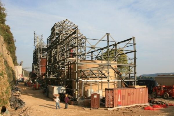 mid-city-steel-pattison-frac-sand-plant-industrial-project-gallery-6 Steel framework of an industrial building under construction with equipment, containers, and workers on site.