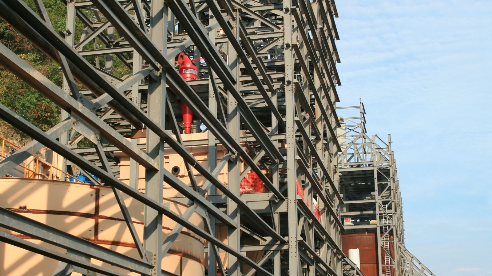 Steel framework of an industrial structure or building under construction against a blue sky.