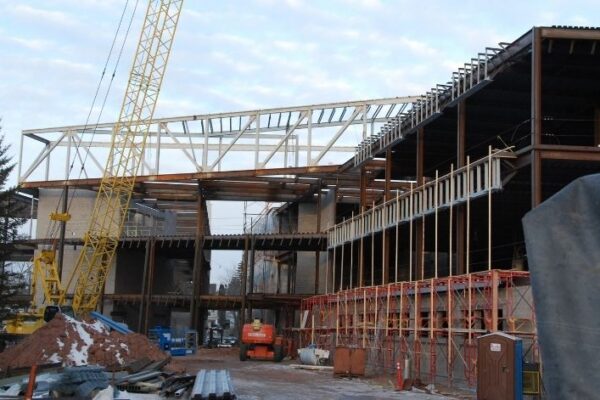 mid-city-steel-uw-superior-swenson-hall-institutional-project-gallery-1 A large building under construction with steel beams, scaffolding, cranes, and construction equipment on site.