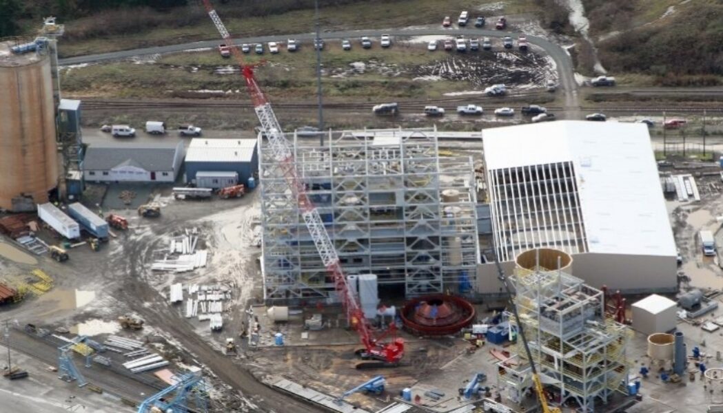 Aerial view of a Mid-City Steel structural steel construction project with multi-story steel framing, cranes, staged materials, and active jobsite operations.