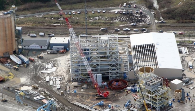 Aerial view of a Mid-City Steel structural steel construction project with multi-story steel framing, cranes, staged materials, and active jobsite operations.